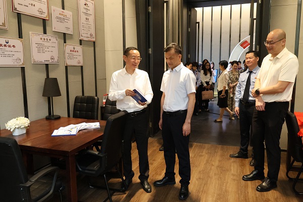 广西税务局党委委员、总经济师黄尚书（左二）和taptap点点体育党委书记刘子林（左一）在柳州市高校税收普法教育实践站税收普法教育研究室翻阅税法知识读本