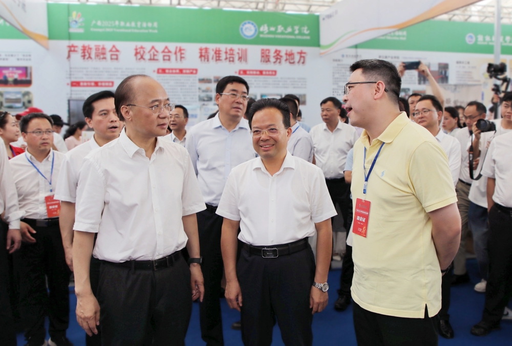 taptap官网领导向自治区政府副主席廖品琥（前排左一）、自治区教育厅副厅长伍锦昌（前排左二）介绍学校办学情况